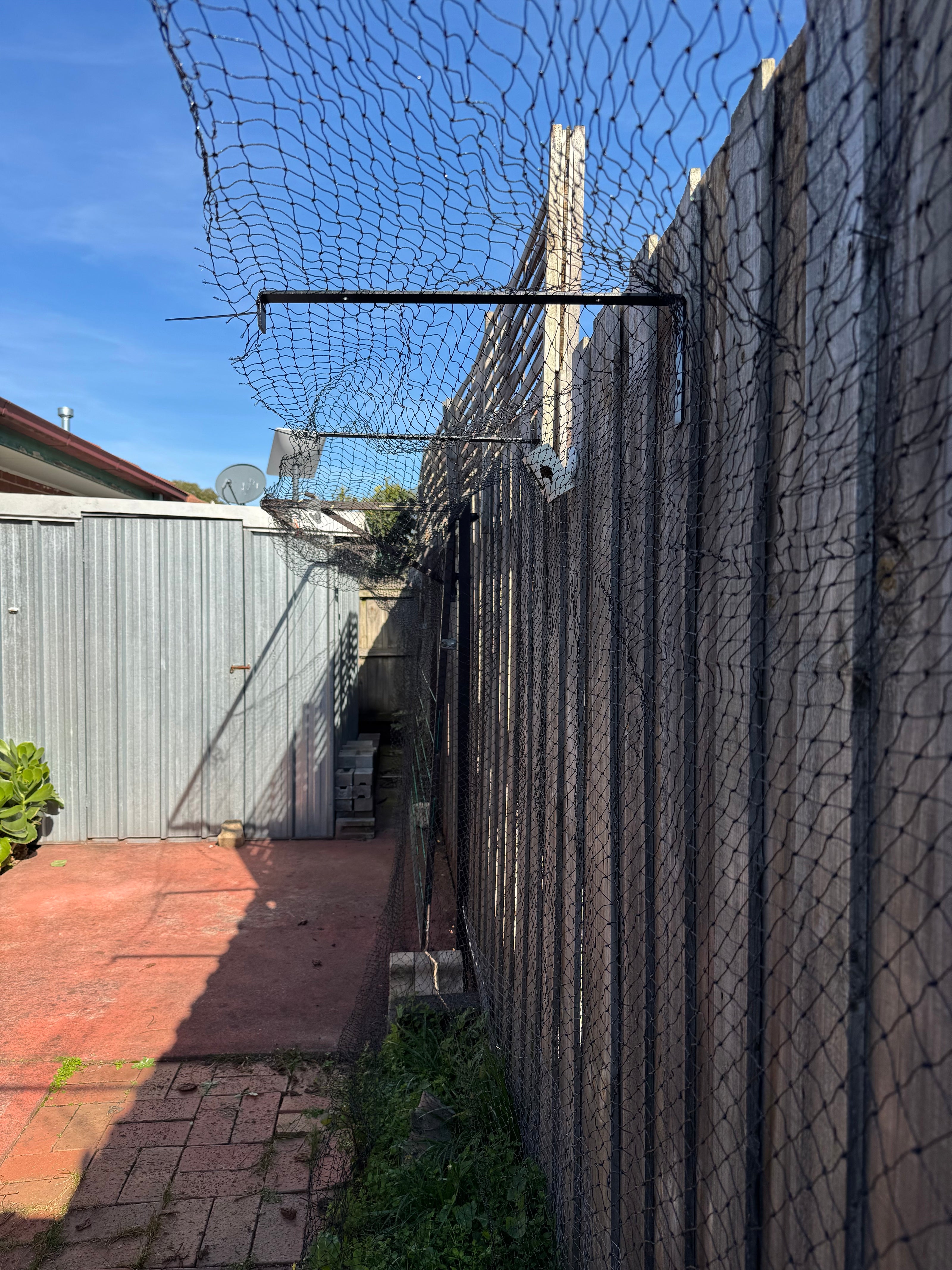 Customers backyard showing the cat net and brackets installed against a fence with a shed in the background